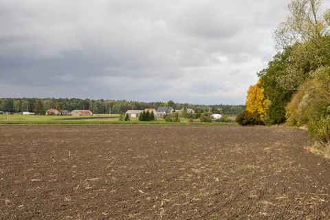 Dark clouds over the plowed field and the village in the background. Autumn. Stock Photos