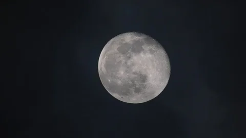 Dark clouds pass moon at night nearly in full phase seen by refractor telescope Stock Footage 123217595