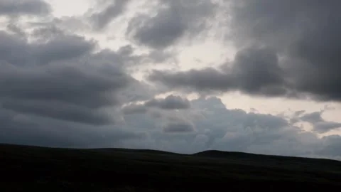 Dark clouds passing over a hilside. Video stock 312698977