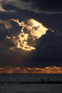 Dark clouds with rays in the center against the background of a sunset over the Foto stock