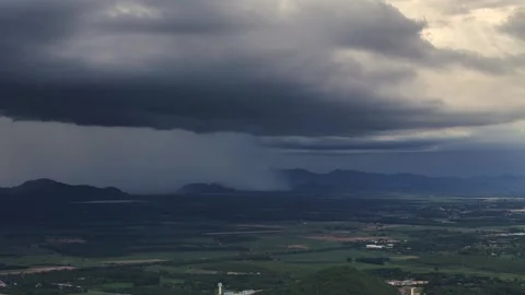 Dark clouds roll over green valley as monsoon rain hits rural farms and forests Stock Footage 318721784