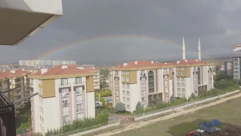 Dark clouds in sky cloudy. Tall buildings in distance. Big bright rainbow in sky Stock Footage 145769576
