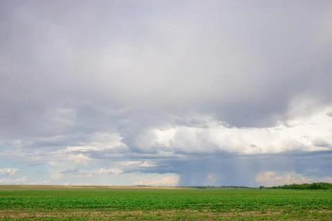 Dark clouds on sky with one part with rain over agricultural fields in distan Stock Photos