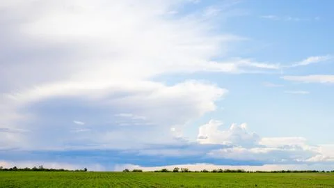 Dark clouds on sky with one part with rain over agricultural fields in distan Stock Photos