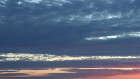 Dark clouds slowly float across the sky at sunset, illuminated by the rays of th Stock Footage 214011012