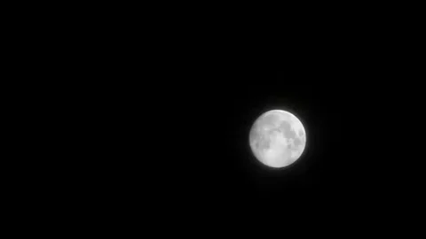 Dark clouds slowly moving through the full moon, shining on a black Stock Footage 98247080