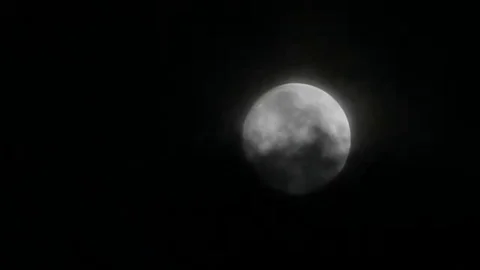 Dark clouds slowly moving through the full moon, shining on a black sky Stock-Footage 98247084