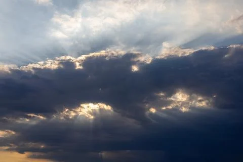 Dark clouds with sun rays breaking through sky Stock Photos