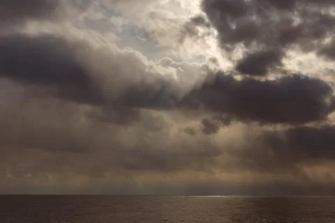 Dark Clouds with Sunbeams Breaking Through the Sea Stock Photos