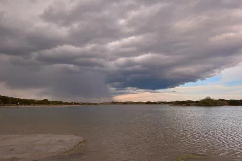 Dark clouds in sunset over the lake Stock Photos