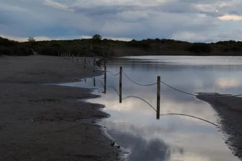 Dark clouds in sunset over the lake with a railing Stock Photos