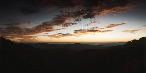 Dark clouds in the sunset sky over the silhouetted mountain ranges Stock Footage 103397532