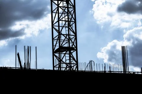Dark cloudy sky at building construction site silhouette crane. Investment bu Stock Photos