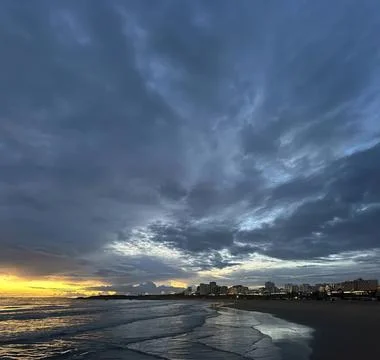 Dark cloudy sky over a beach at sunset with waves Stock Photos