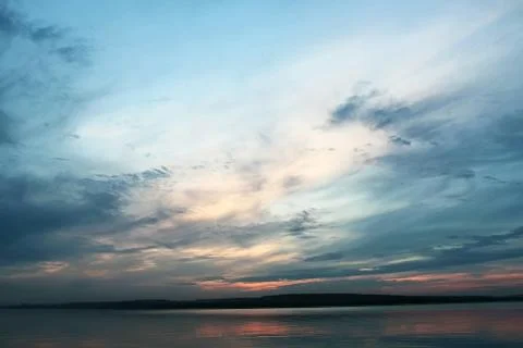 Dark cloudy sky at sunset over the lake Stock Photos