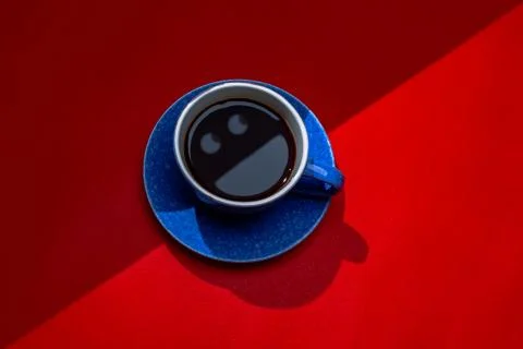 Dark coffee in cup on red background with smiley face. Stock Photos