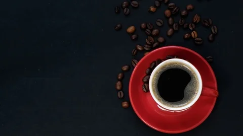 Dark coffee in red cup and coffee beans on black table with copy space. Top view Stock Footage 125292483