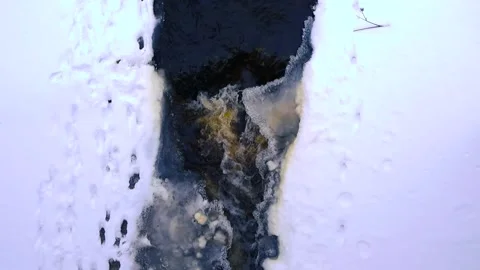 Dark Cold River Water Flowing Between Snow and Ice Video stock 334090606