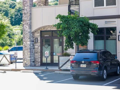 Dark compact crossover SUV car parked in front of a modern commercial offic.. Stock Photos