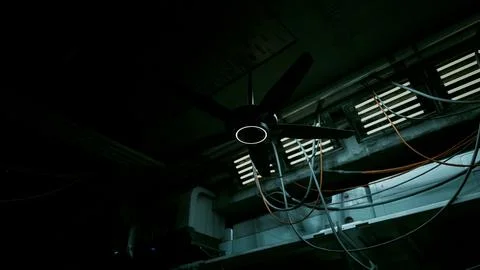 A dark concrete interior with a ceiling fan and multiple wires hanging from i Stock Illustration