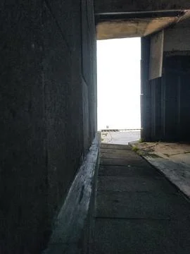 Dark concrete passage featuring a bright, white opening at the end, creating  Stock Photos