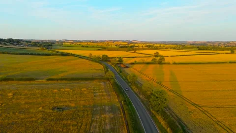 Dark convertible car driving along winding countryside road between golden Stock Footage 345126442