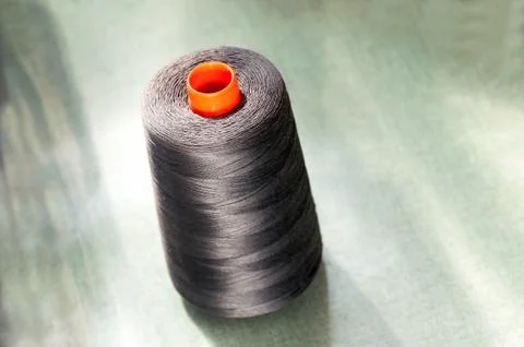 Dark cotton thread on an orange upright spool Stock Photos