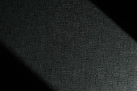 Dark creative background: black primed linen canvas, uneven lighting, toning Stock Photos