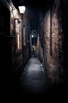 A dark creepy narrow European alley at night, surrounded by bricks and Stock Photos