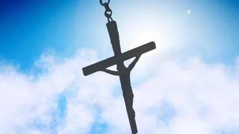Dark cross pendant swinging while sun backlighting halo, clouds drifting, Video stock 328331109