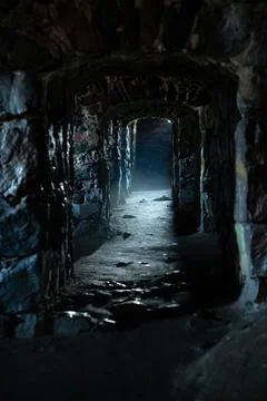 A dark, damp, cold dungeon corridor with stone walls all along the hallway Stock Photos