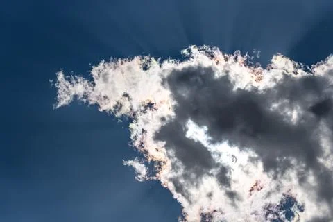 Dark dramatic cloud obscuring the sun with visible light rays Stock Photos
