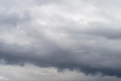 Dark dramatic clouds gathering above horizon, heavy layered cloudbase, deep s 写真素材