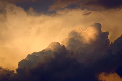 Dark, dramatic nimbus clouds at sunset, lit by the last rays of sunlight befo Stock Photos