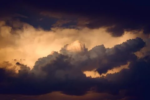 Dark, dramatic nimbus clouds at sunset, lit by the last rays of sunlight befo Stock Photos