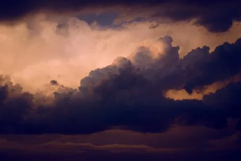 Dark, dramatic nimbus clouds at sunset, lit by the last rays of sunlight befo Stock Photos