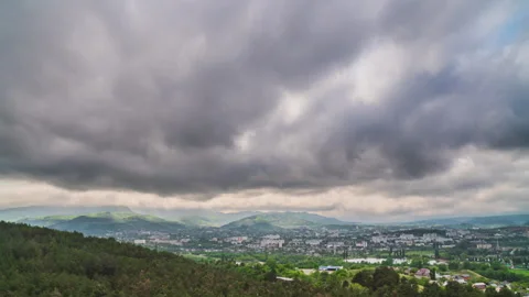 Dark dramatic sky with heavy rain over green hills, provincial town and forest Stock Footage 276232782