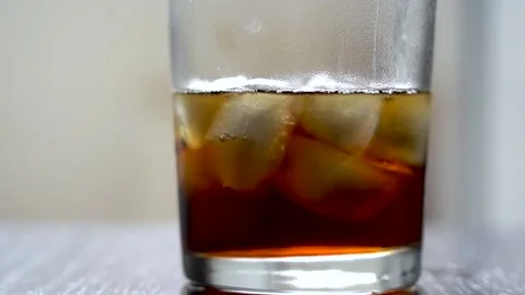 Dark drink in a glass with ice on the table. Cold refreshing cola in a glass Stock Footage 144425009