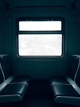 Dark empty cabin of a passenger train car with seats and a window in the cent Stock Photos
