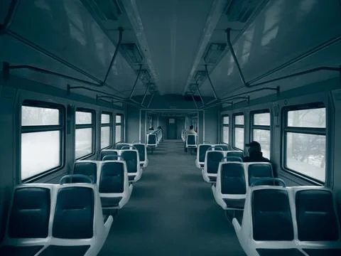 Dark empty cabin of a passenger train car with seats. Stock Photos