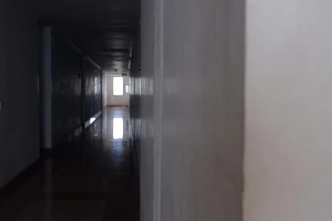 Dark Empty Corridor Leading to Bright Exit Door in Jakarta Residential Apartment Foto stock