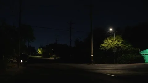 Dark empty intersection at night illuminated by a lone streetlight Stock Footage 346920073