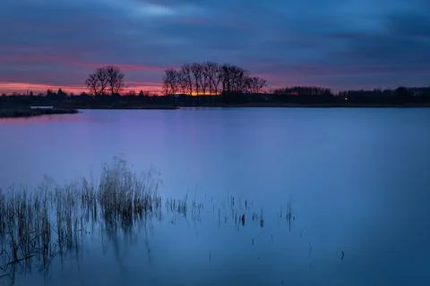 Dark evening clouds after sunset and reeds blown away from the wind on the la Stock Photos