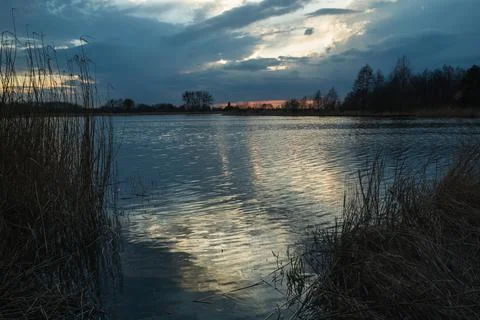 Dark evening clouds over the lake and light reflection in the water Stock Photos