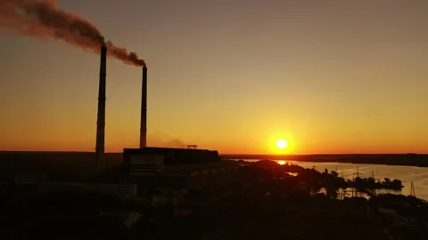 Dark factory against the orange setting sun. Factory pipes with smoke. Stock Footage 135400334