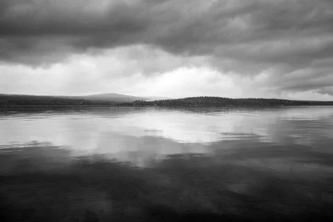 Dark, Foreboding Storm Clouds Over A Gloomy Gray Lake Landscape Stock Photos
