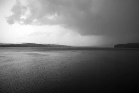 Dark, Foreboding Storm Clouds Over A Gloomy Gray Lake Landscape Stock Photos