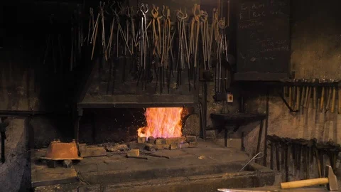 Dark forge with fire burning next to anvil and locksmith's hammer Stock Footage 124476308