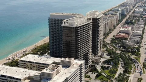 Dark glass tower over the sand and shallow surf in Bal Harbour, Florida Vidéo 100097579
