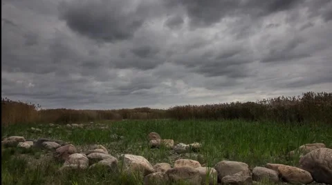 Dark gloomy clouds move over the field and stones timelaps Video stock 57171894
